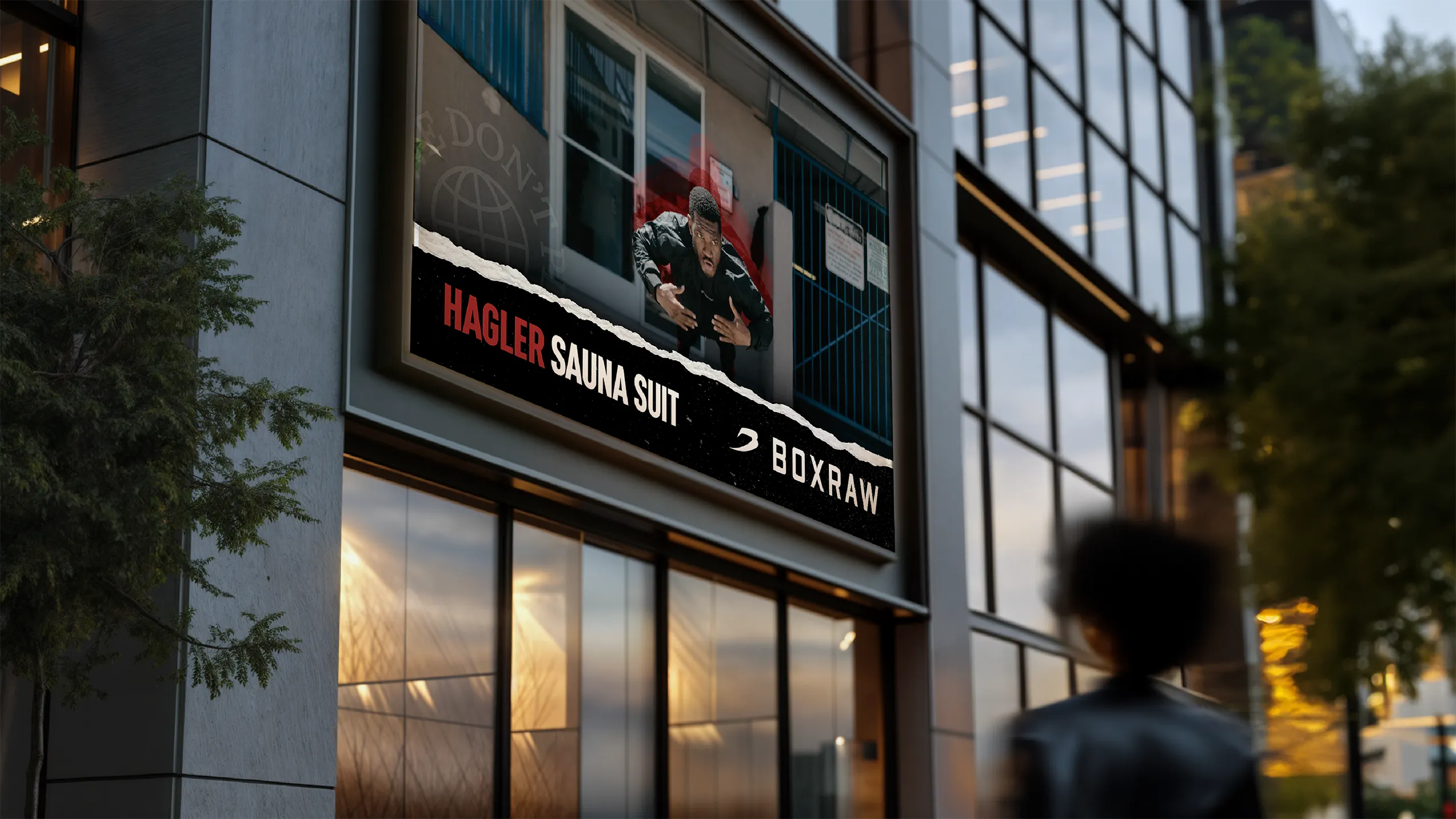 Hagler Sauna Suit billboard above a BOXRAW storefront at dusk.