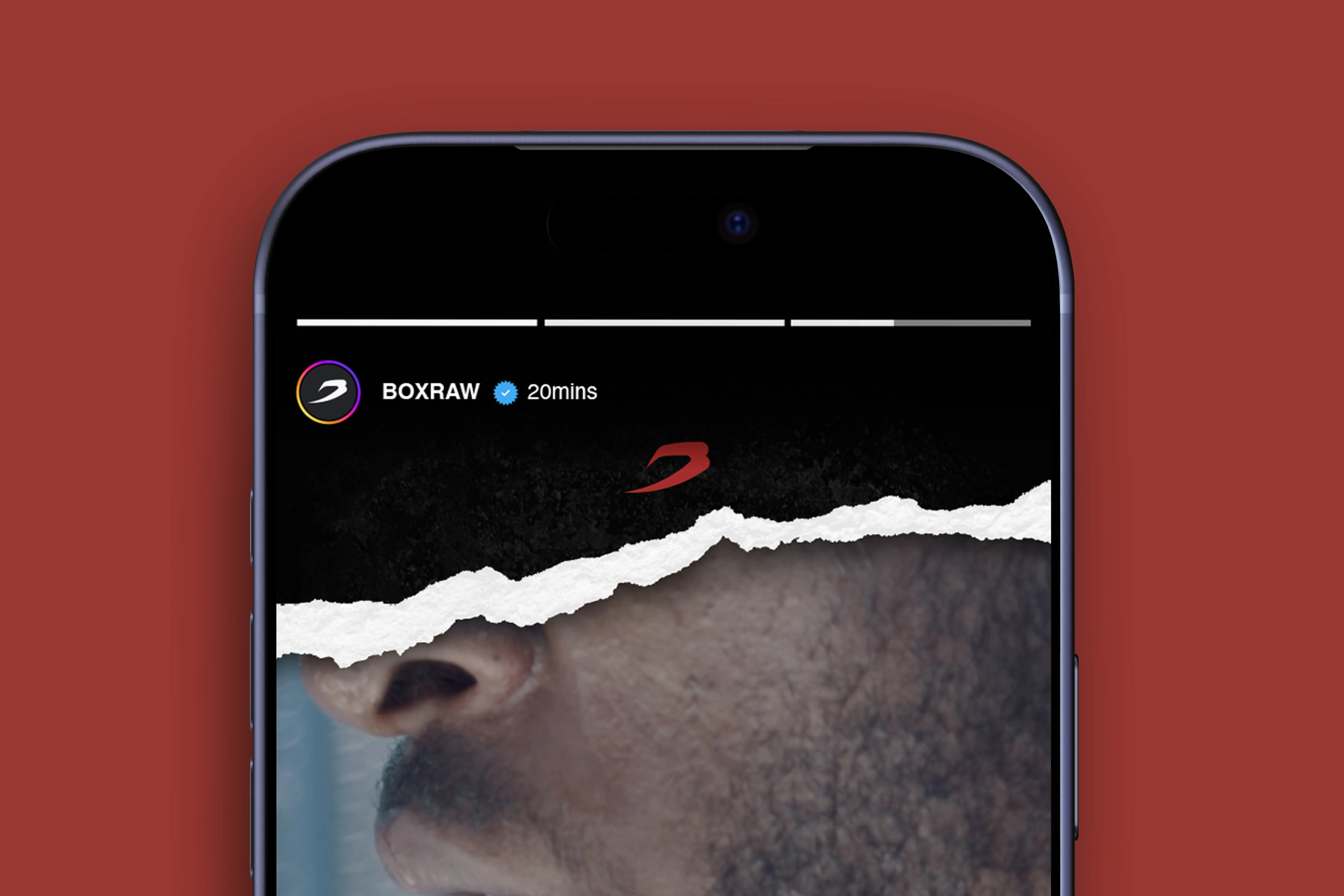 A phone on a brick-red backdrop playing the BOXRAW campaign Instagram Story.