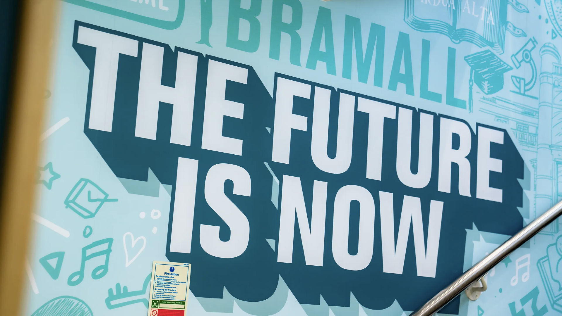 Close view of the 'The future is now' mural, showing the layered drop shadow and the teal doodle background behind it