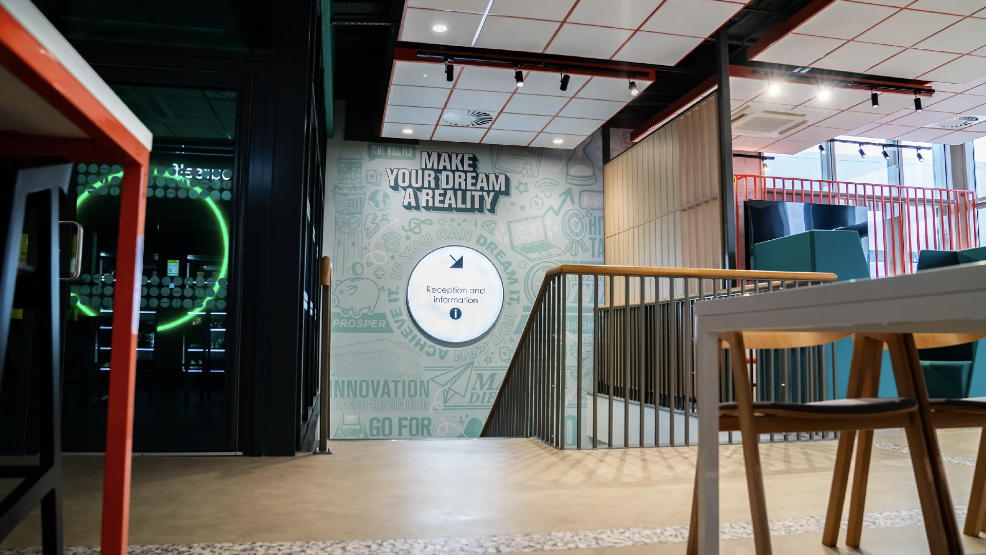 Wide view of the reception landing, with the 'Make your dream a reality' wall graphic beyond the balustrade and study seating in the foreground